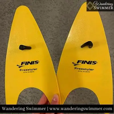 Image of someone holding two yellow, regular FINIS Freestyler Paddles