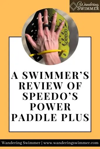Image with a light orange background. A circle at the top of a white text box has a right hand wearing a yellow Speedo Power Paddle plus paddle. Text below the picture reads: A Swimmer’s Review of Speedo Power Paddle Plus