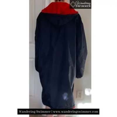 Image of a person wearing an a dark navy and red Adoretex swim parka. The view is from the back to show the hood and the length of the parka on the person