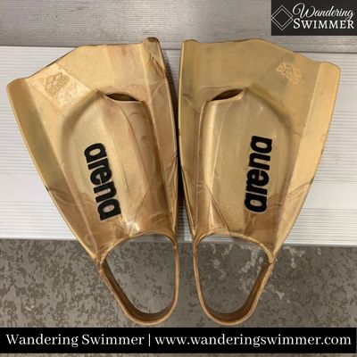 A pair of golden Arena Power Pro Fins sitting on a metal bench