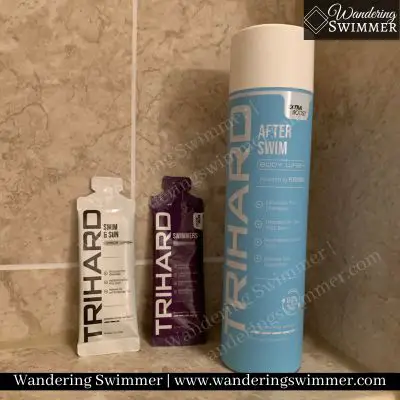 Image of a bottle of TRIHard Body Wash with two sample packets of face wash and shampoo sitting on a shower ledge